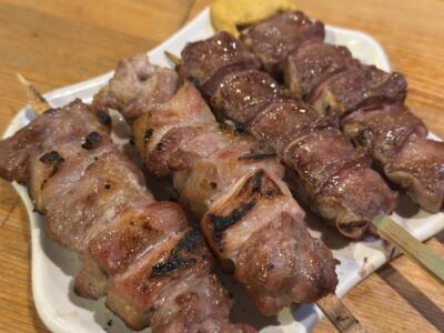 竹串に刺さった香ばしい焼き鳥。豚バラ肉と赤身肉があり、美味しそうに焼けている。