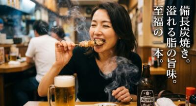 女性が焼き鳥を一口食べ、幸せそうな表情をしている。テーブルにはビールとホッピーがある。