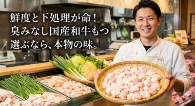 笑顔の男性が新鮮な国産和牛のもつを手に持ち、厨房で野菜と共に並べられている様子